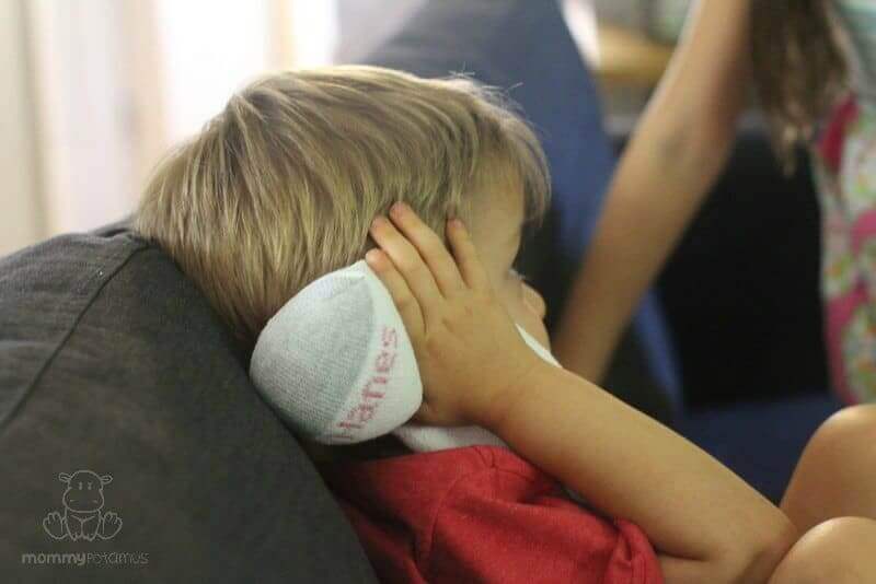 Child holding salt sock earache remedy over ear